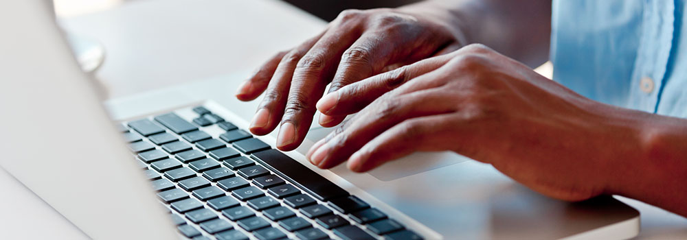 Banner image of hands on a computer keyboard