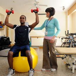 Picture of a patient on a bouncy ball lefting weights
