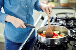 Young person cooking vegetables in a large saucepan