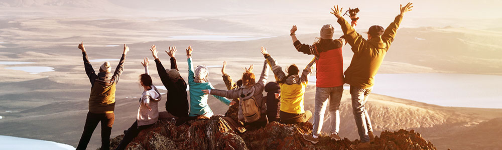 Group of People standing/celebrating on top off a mountain