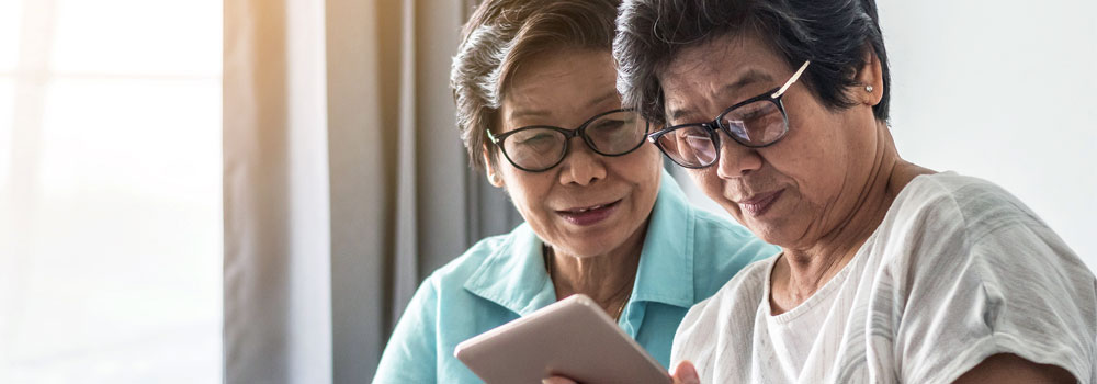 two seniors reading information of a tablet