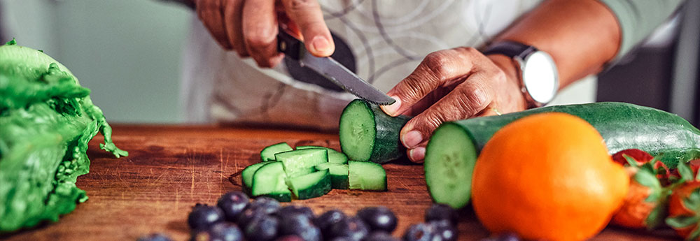 person slicing a cucumber