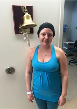 Emily at her last chemo, standing beside the Bravery Bell