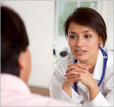 Female doctor sitting and leaning towards patient in conversation