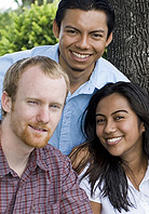 Three smiling people standing together outside