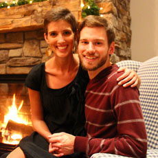 Julia and her husband sitting on a couch in front of a fireplace