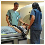 Two radiation therapists standing on either side of a patient lying down before radiation therapy
