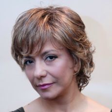 Female cancer survivor wearing short, curly, light brown human hair wig