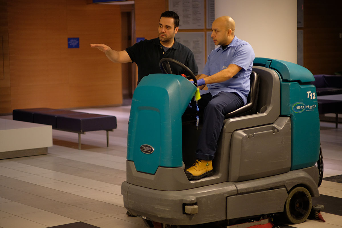 Two guys with riding cart floor cleaning machine