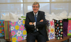 Picture of Bob Bell smiling with present bags behind him