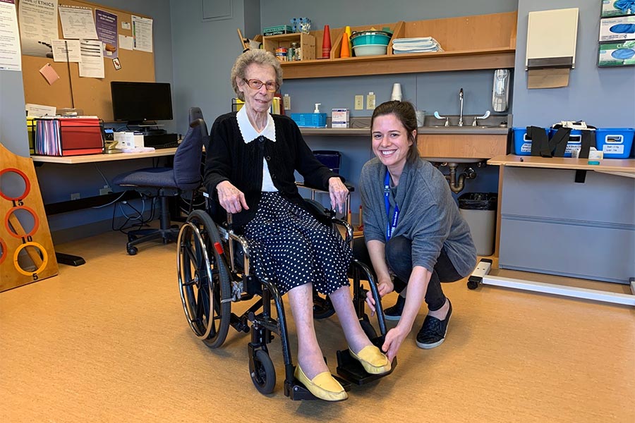 OT crouching beside patient in a wheelchair 