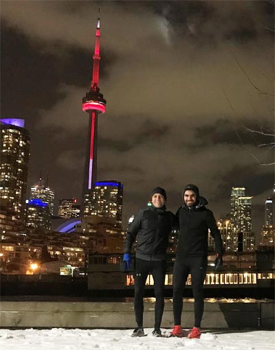 Two guys together with bright CN Tower 
