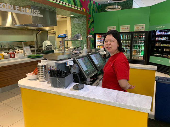 Young woman at cash register in cafeteria 