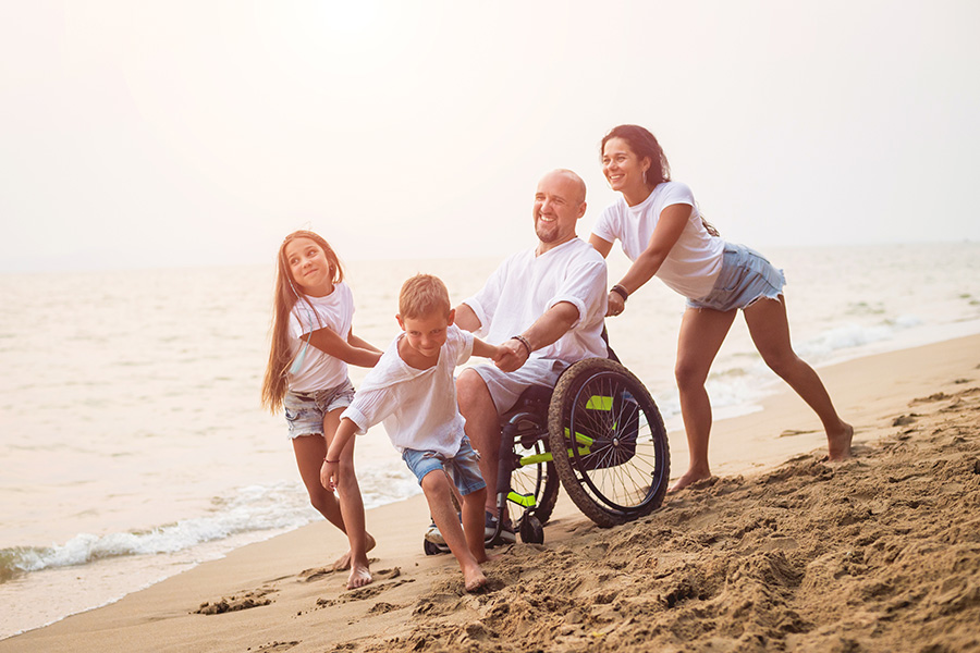 family with wheelchair on beach 