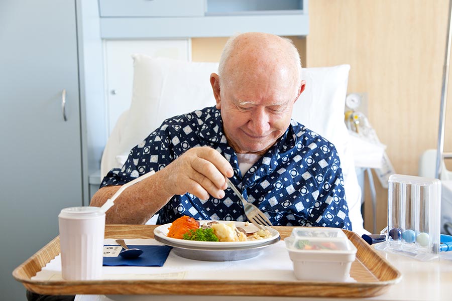 man eating in hospital bed 