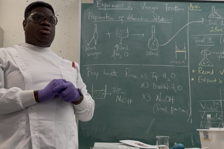 Ferdinand Reke Avikpe in front of a chalk board