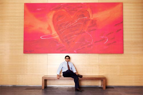 Dr. Husain seated underneath big heart painting