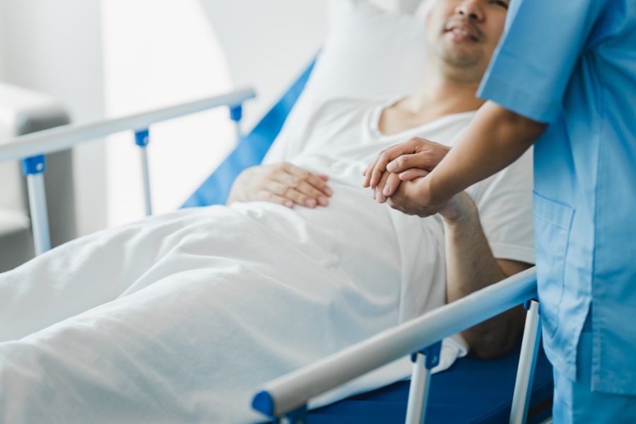 Doctor holding patient's hand while patient is in hospital bed