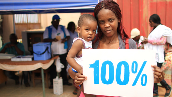 Image of Mother and child holding a sign indicating “100%”