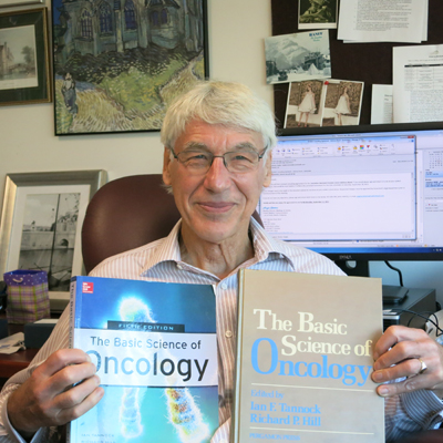 Tannock poses with the first edition of ‘The Basic Science of Oncology’