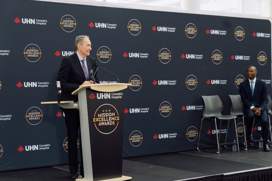 UHN CEO, Kevin Smith speaking at the podium on stage