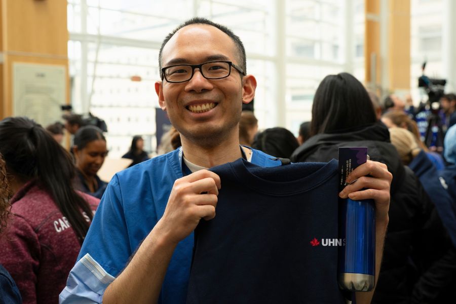 TeamUHN member holding second to none sweatshirt