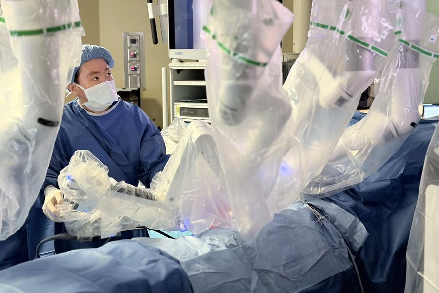 Surgeon performs robotic surgery in an operating room.