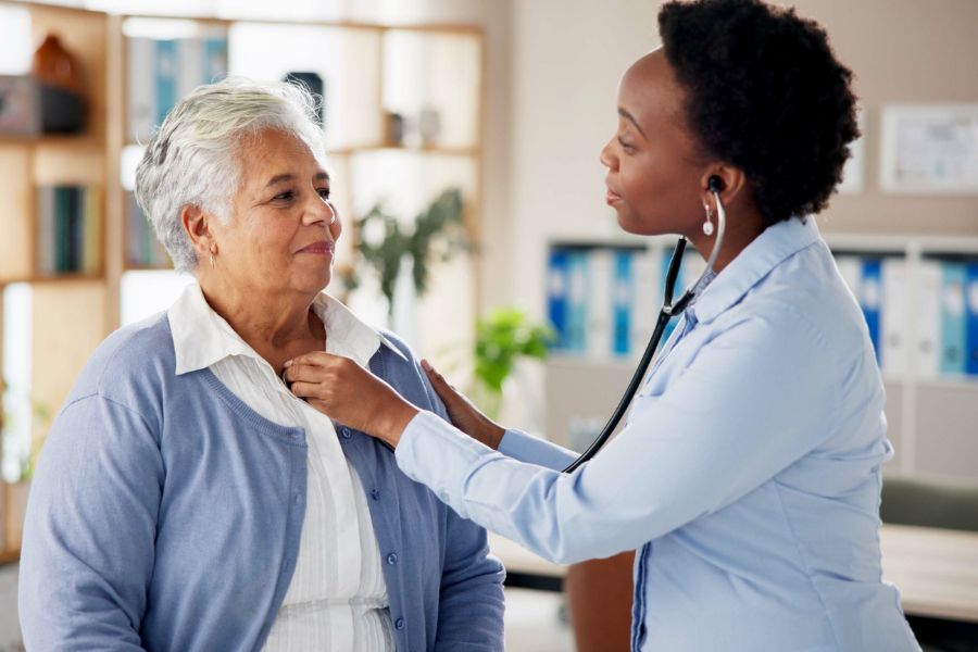 Woman doctor and senior person with stethoscope