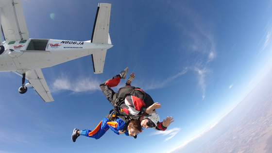 Woman and skydiving instructor jumping out of plane